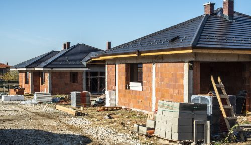 Building a new brick house with black roof. Small houses on cons